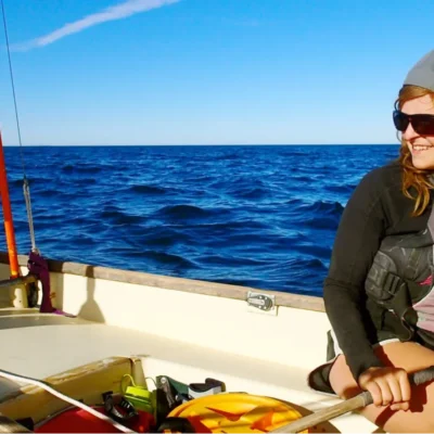 A smiling student tending to the rudder while sailing on the Sea of Cortez in Baja California, Mexico.