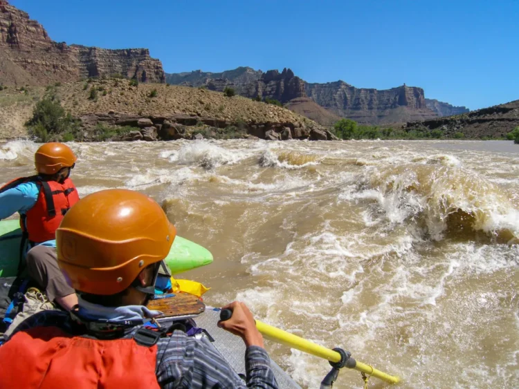 NOLS participants raft through fast-moving white water.