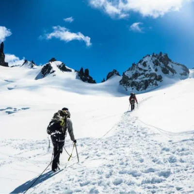Students mountaineer on a snowy slope below sharp, unclimbed spires in southern Chile.