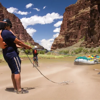 Students pulling rafts onto the shore in a canyon.