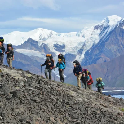 Students trek up the side of a mountain with the scenic Wrangell Mountains providing an epic backdrop.