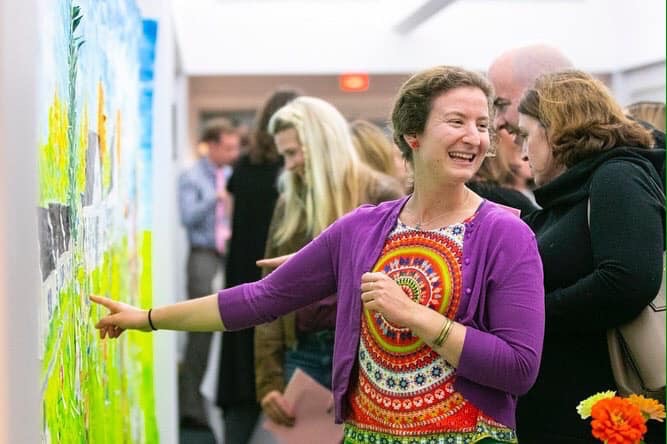 Teacher smiling and pointing out art on the wall