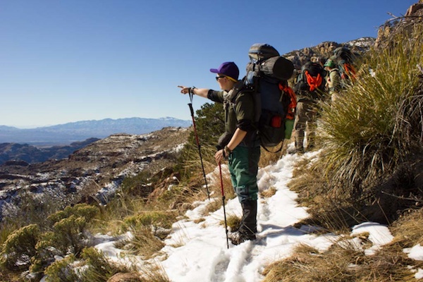 NOLS backpacking student points toward mountains in the Southwest