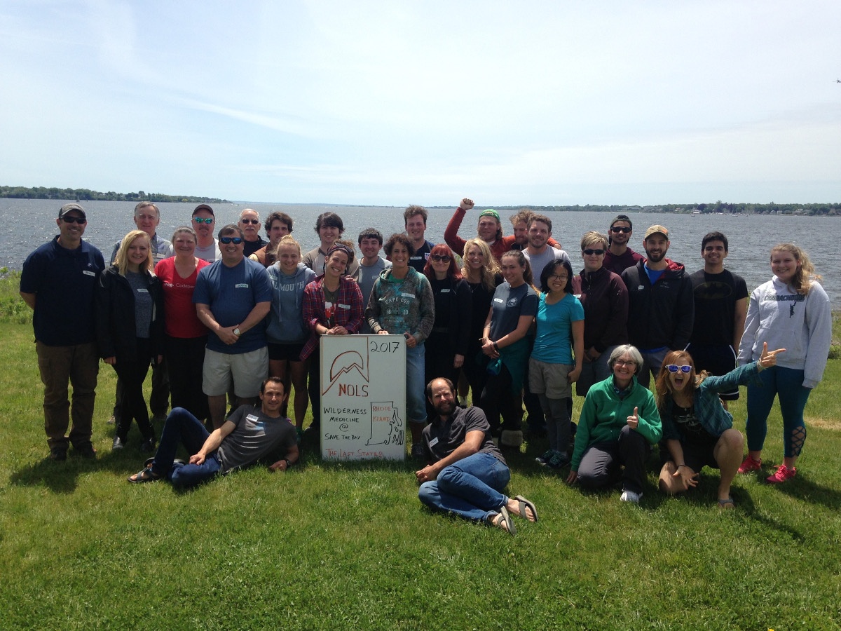 smiling students at NOLS' first wilderness medicine course in RI pose for a group shot with the Narragansett Bay in the background