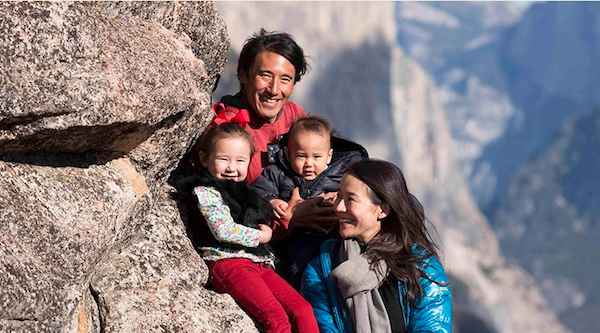 family of four with two young children smile together in the mountains