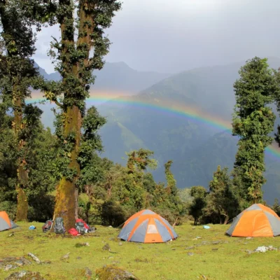 Student tents high up in the Himalayan wilderness beneath a brilliant rainbow.