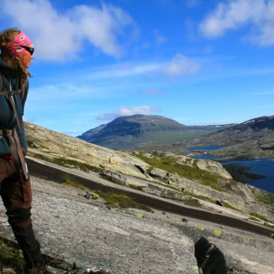 A student on a hill looks off at a lake in the distance while backpacking in Scandinavia. Credit: Cass Colman