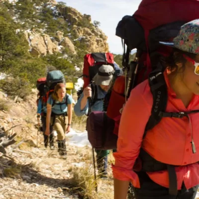Students backpacking uphill through a snow dusted landscape in Arizona's Coronado National Forest. Credit: Eryn Pierce