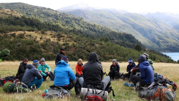 UVA business students sitting in a circle with backpacks in Patagonia with mountains surrounding 