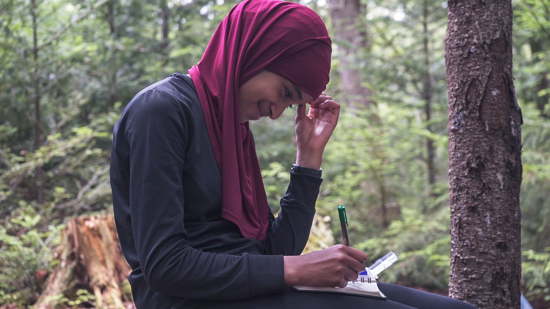 A student smiles while journaling in the Adirondacks