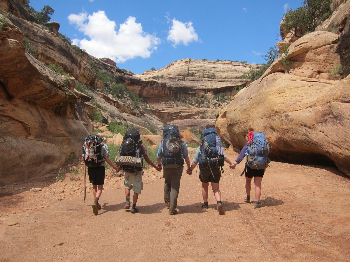 A group hikes through canyons while holding hands