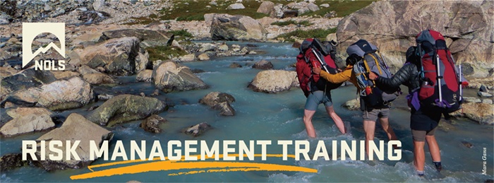Backpackers crossing a river using risk management practices