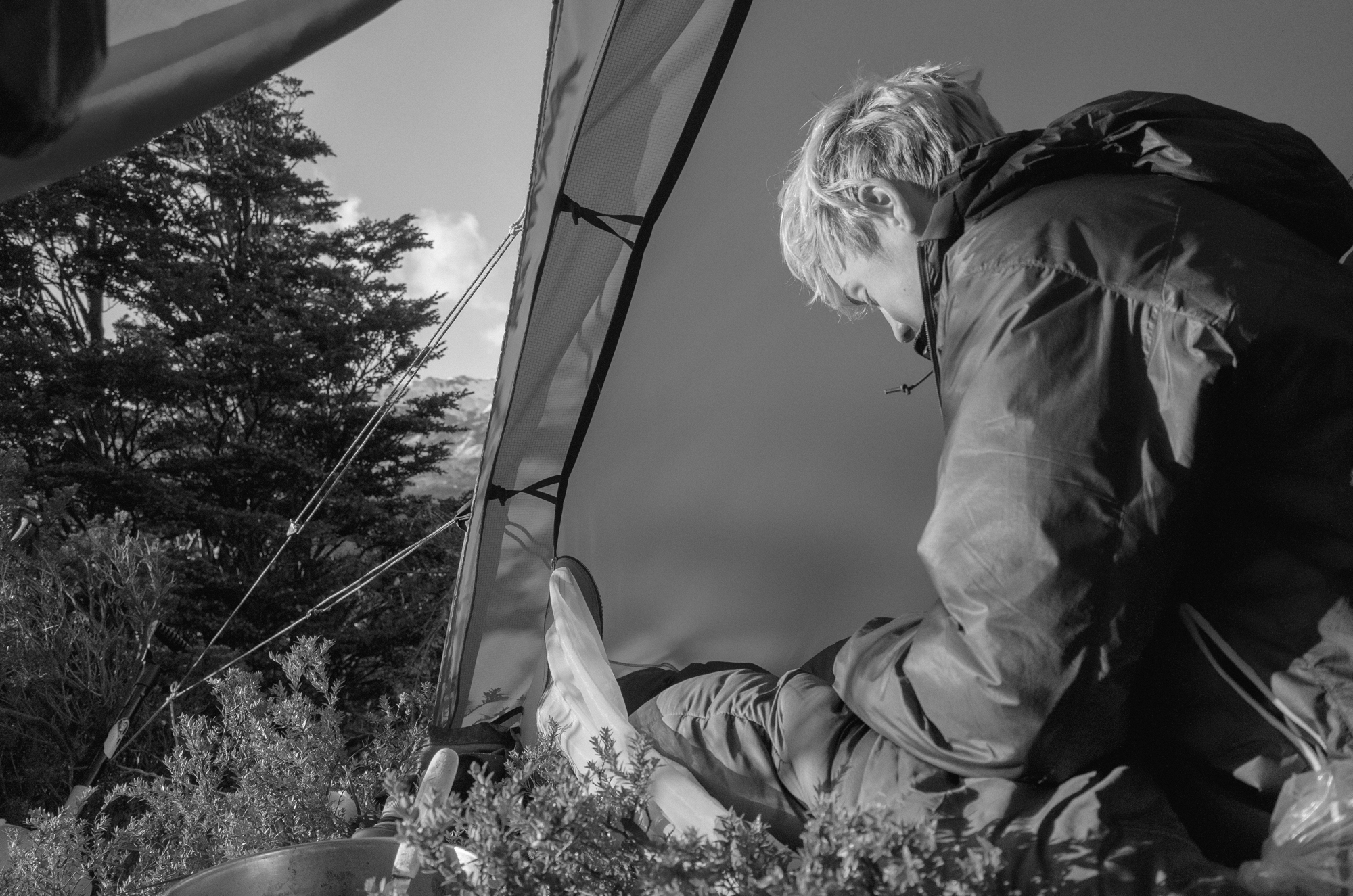 Person sitting outside a tent making breakfast