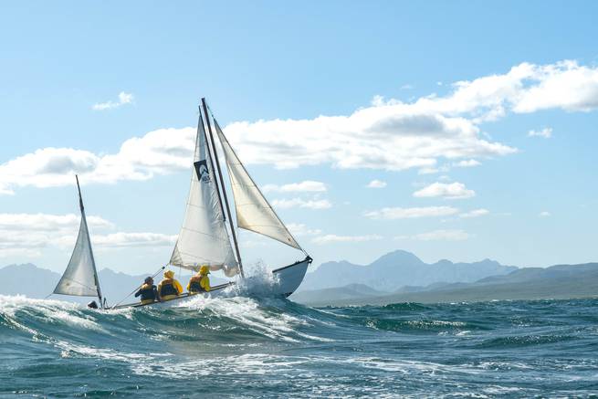 Student enjoying full sails and clear skies while sailing.
