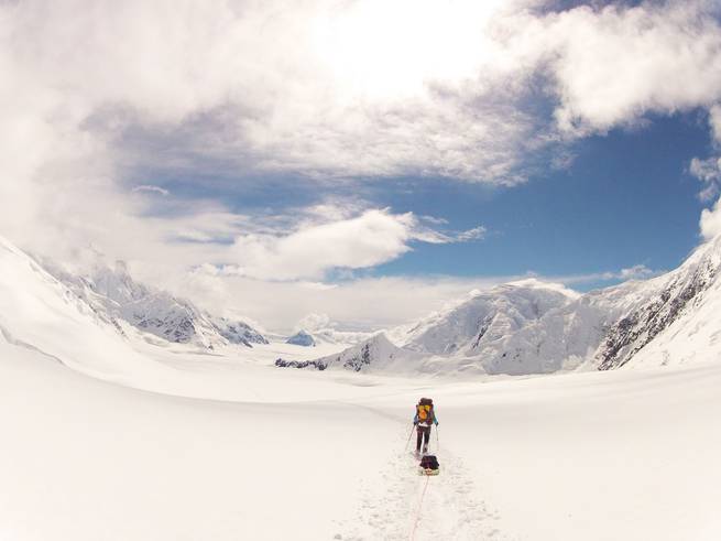 A student with a pack sled travels through a snow-covered landscape in Alaska on their way to Denali.