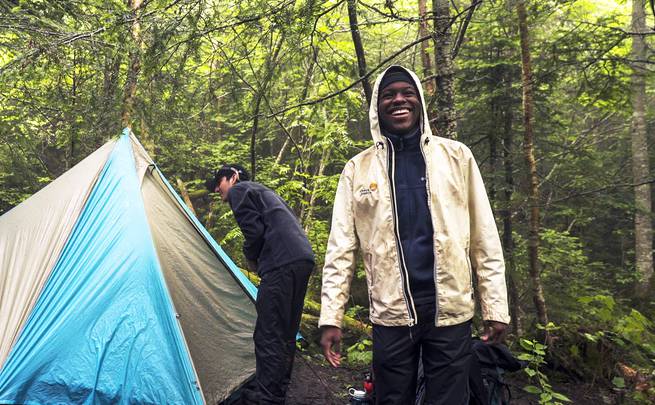 A student laughs while setting up tents in camp.