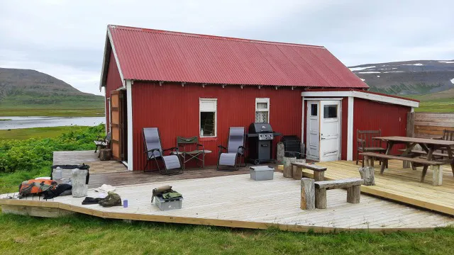a small red house with a large low wooden deck. 
