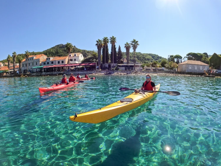 Kayakers paddle through clear blue water in Croatia