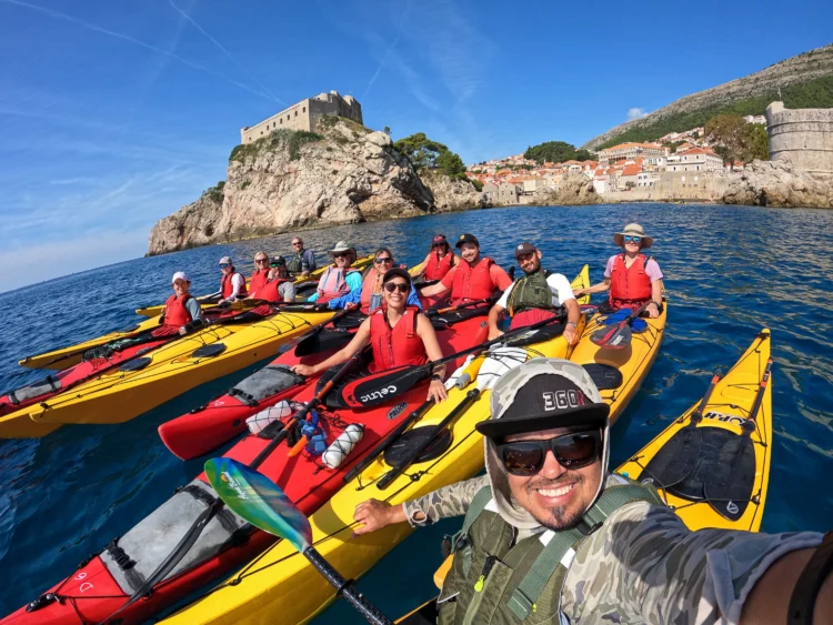 Group of sea kayakers smile with boats lined up in Croatia
