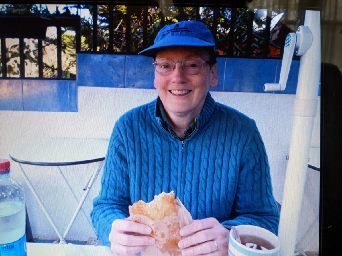 Lou Gordon, dressed in blue, enjoying a sandwich outdoors.