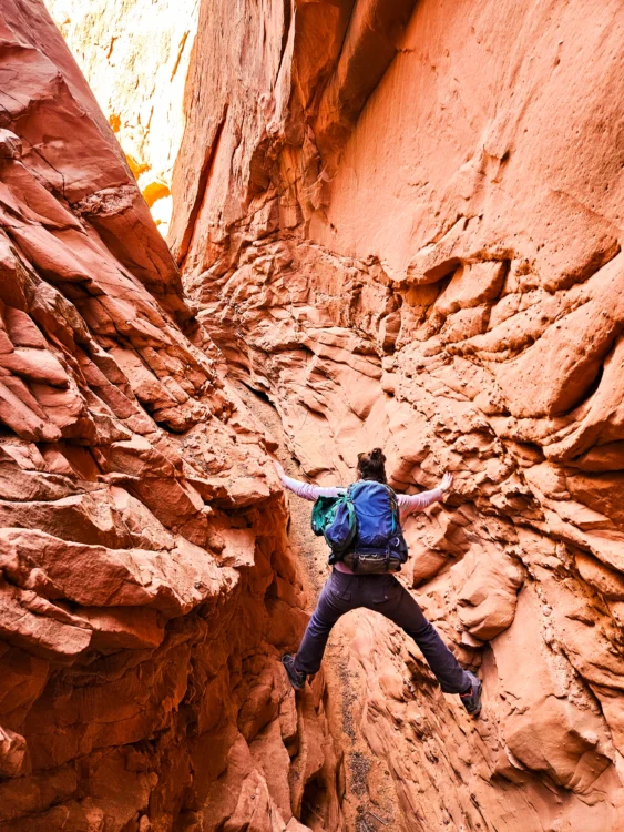 Climber straddles the red canyon walls