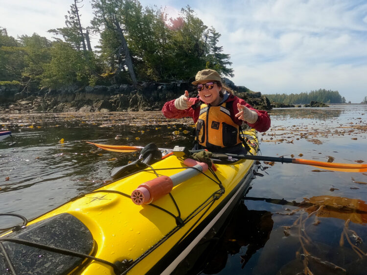 Kayaker gives two thumbs up while sitting in her kayak