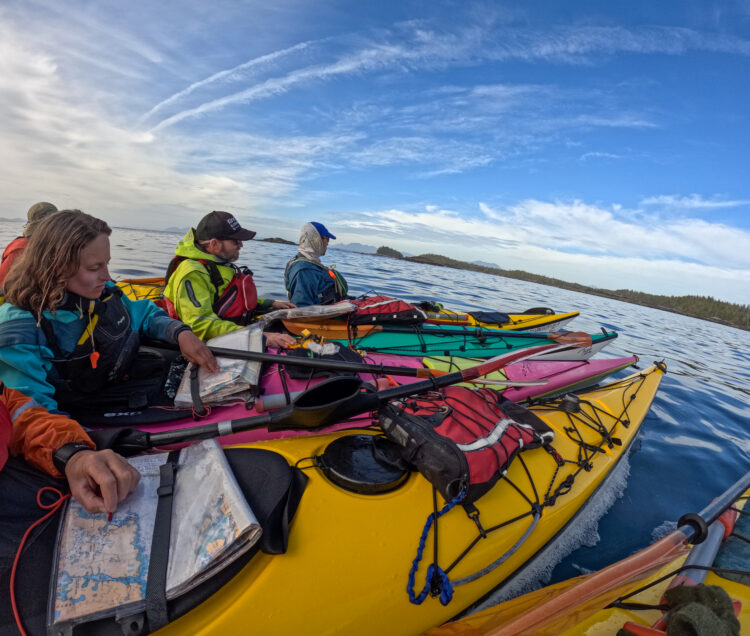 Kayakers look at the map while sitting in their boats in the sea
