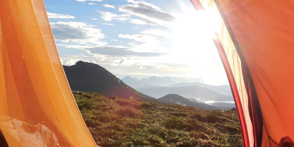 oscar-faust-sca-3-edit.jpg__1400x503_q70_crop_subject_location-2304,1733_subsampling-2_upscale The view of a sunrise while peeking out of the entrance to a tent.